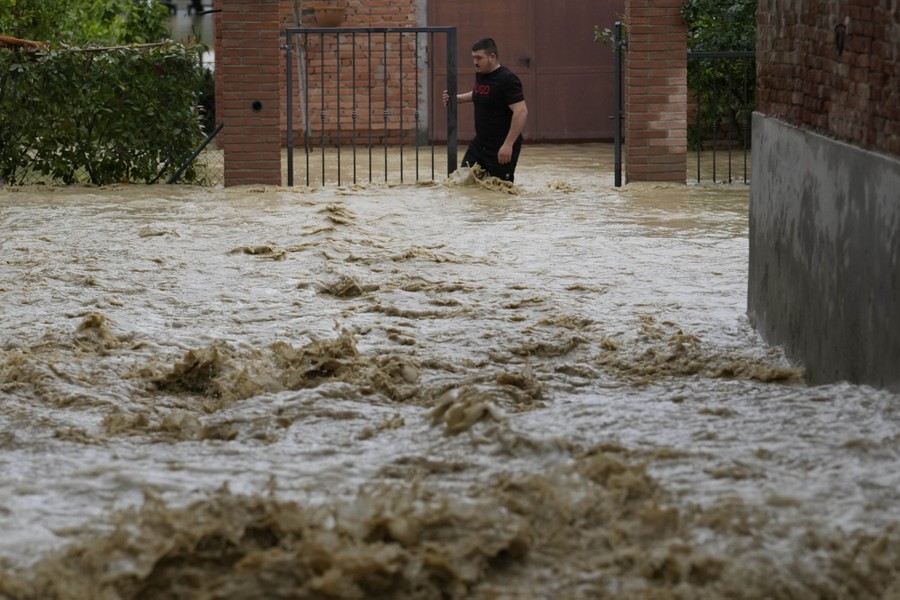 Floodwater splashes as it flows down a street.