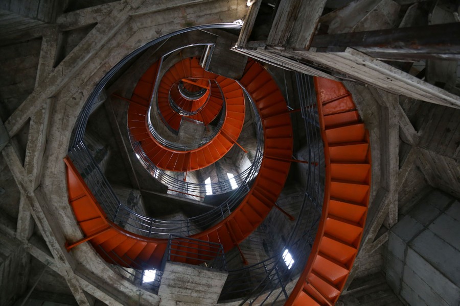 A view looking up, inside a cathedral tower, with a red spiral staircase winding to the top.