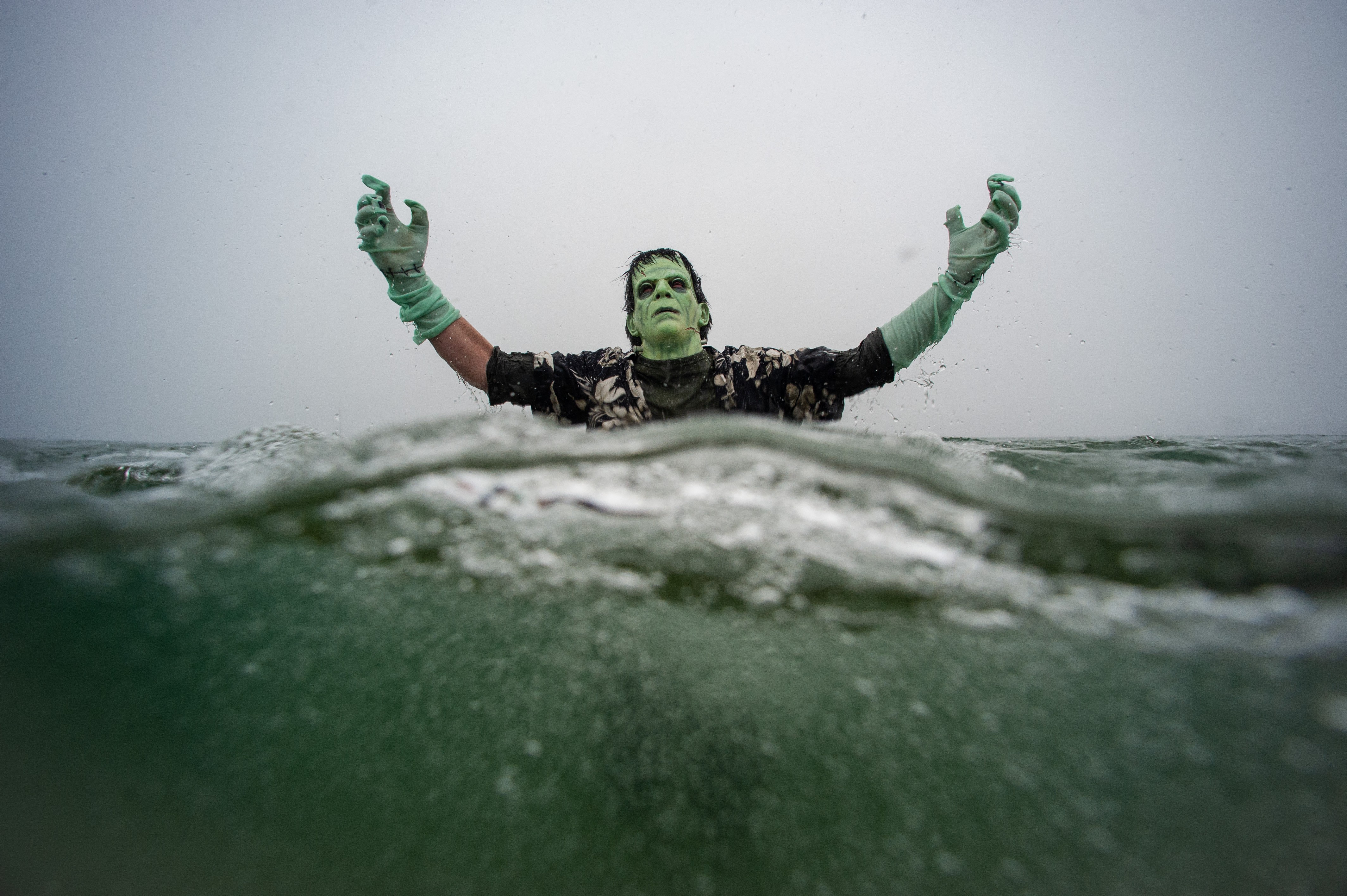 A reveler dressed as Frankenstein's monster plunges into the ocean during a polar bear plunge event.