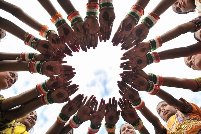 The outstretched hands of Indian girls wearing tricolored bangles form a circle