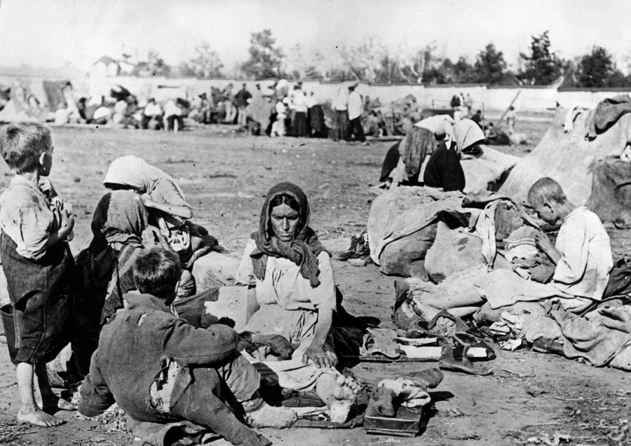 Hungry people sit together in a camp.