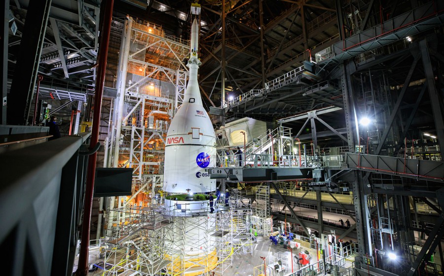The top section of a rocket is set in place, among massive support structures.