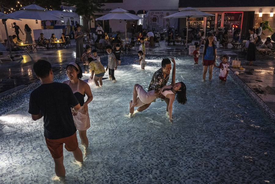 A small crowd of people wade and dance in a shallow pool.