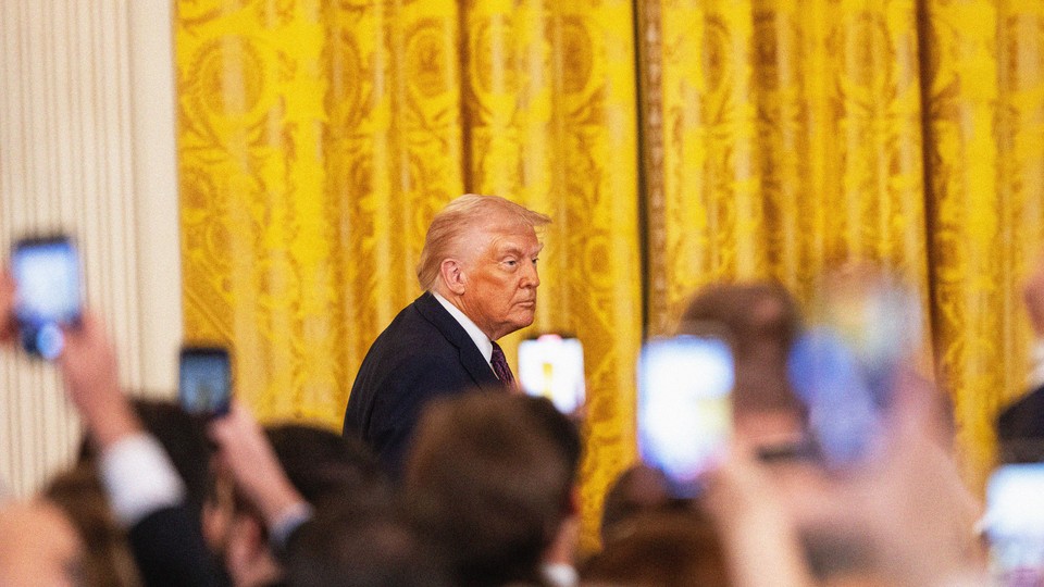 Photo of Donald Trump walking in the White House while onlookers record him via smartphones