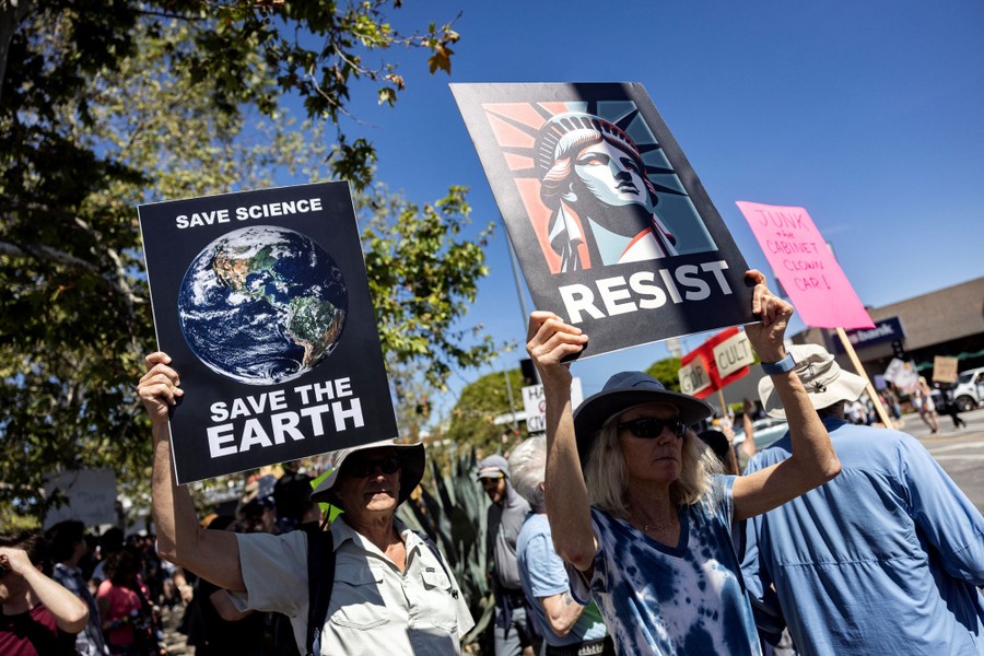 Protesters carry signs, including one with an image of the Earth and text reading "Save science, save the Earth."