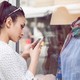 A woman uses a smartphone to take a picture of clothing on a mannequin.