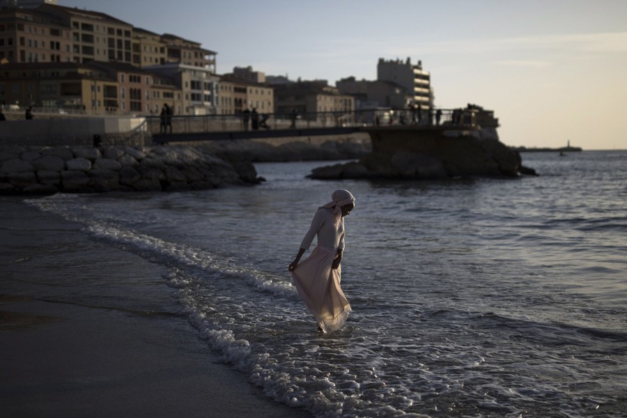 A woman dips her feet in the sea.