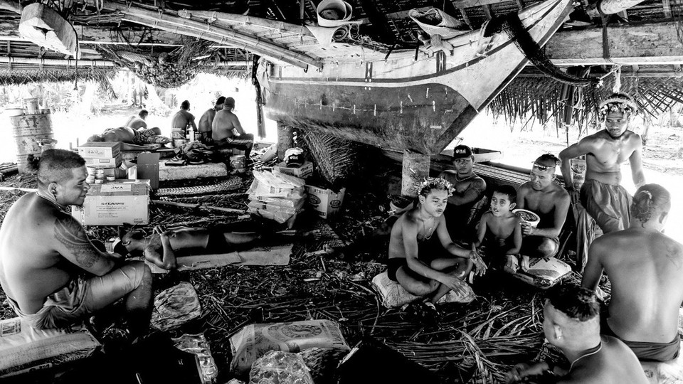 A group of people sit around a boat.