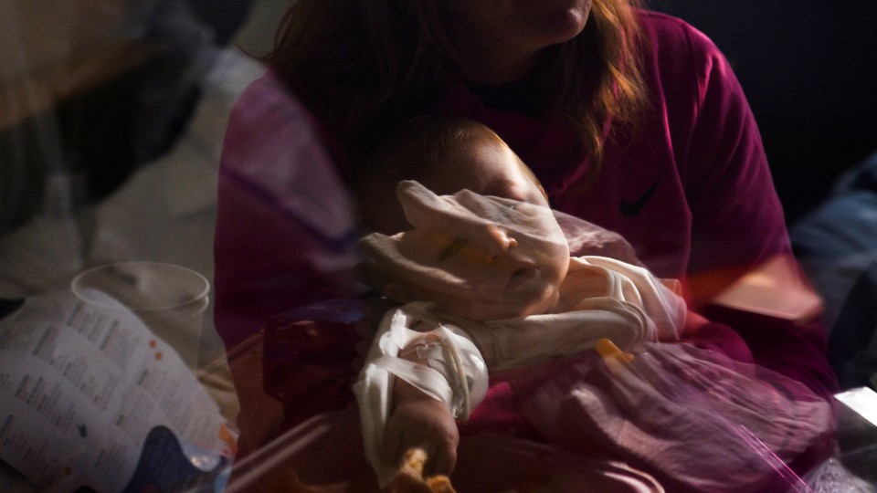 Photograph, taken through a window, of a baby in intensive care