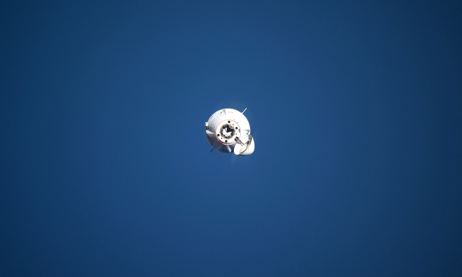 A small spacecraft, seen in orbit, with a vast blue ocean in the background.