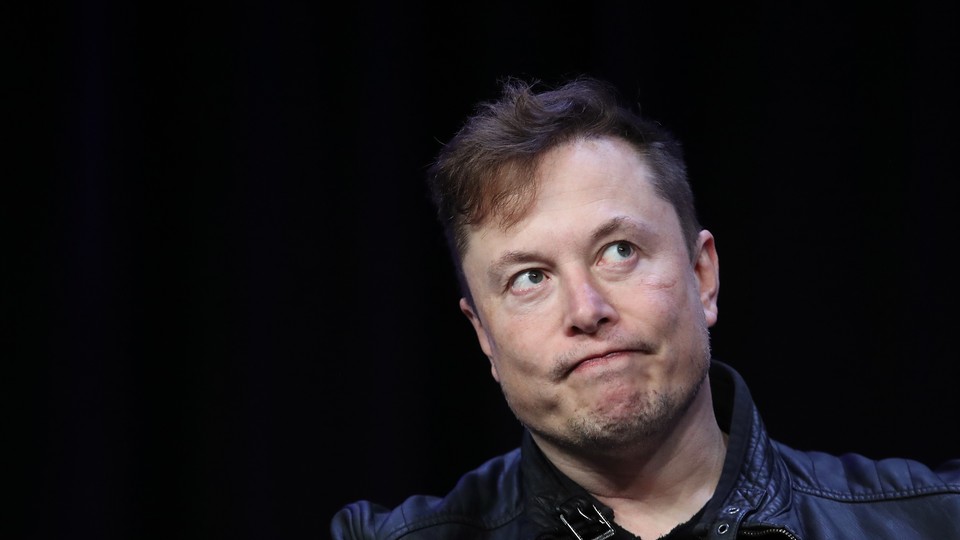 Elon Musk looks up out of the corners of his eyes, frowning slightly.