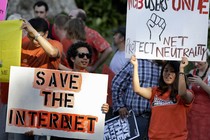 Activists hold signs at a rally for network neutrality.