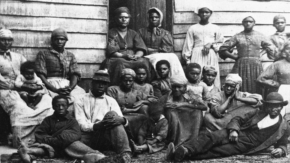 A black-and-white image of Black Americans in front of a cabin