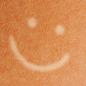 illustration of tanned skin with pale smiley face drawn on it