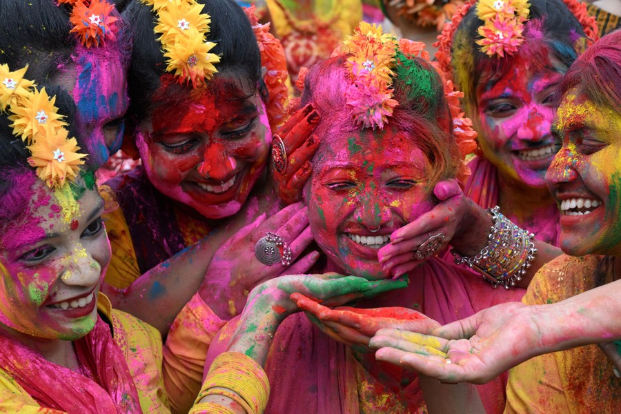 A half-dozen people playfully smear colored powder over each other's faces.