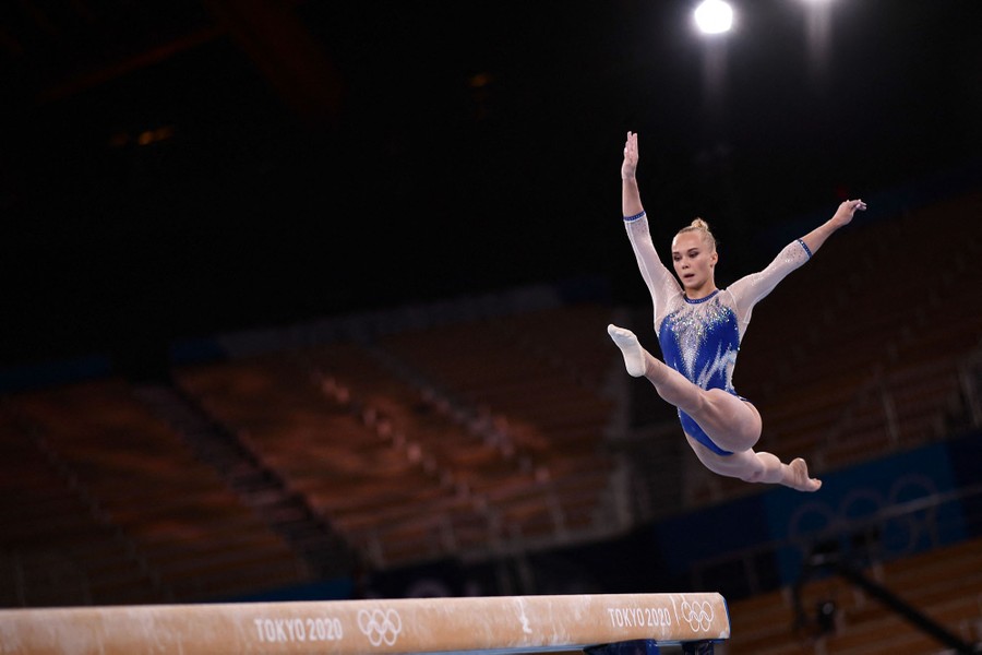 A gymnast leaps above a balance beam.