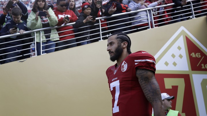 Colin Kaepernick walks out of a tunnel before an NFL football game.