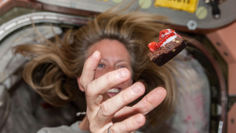 NASA astronaut Karen Nyberg floats a piece of food during mealtime.