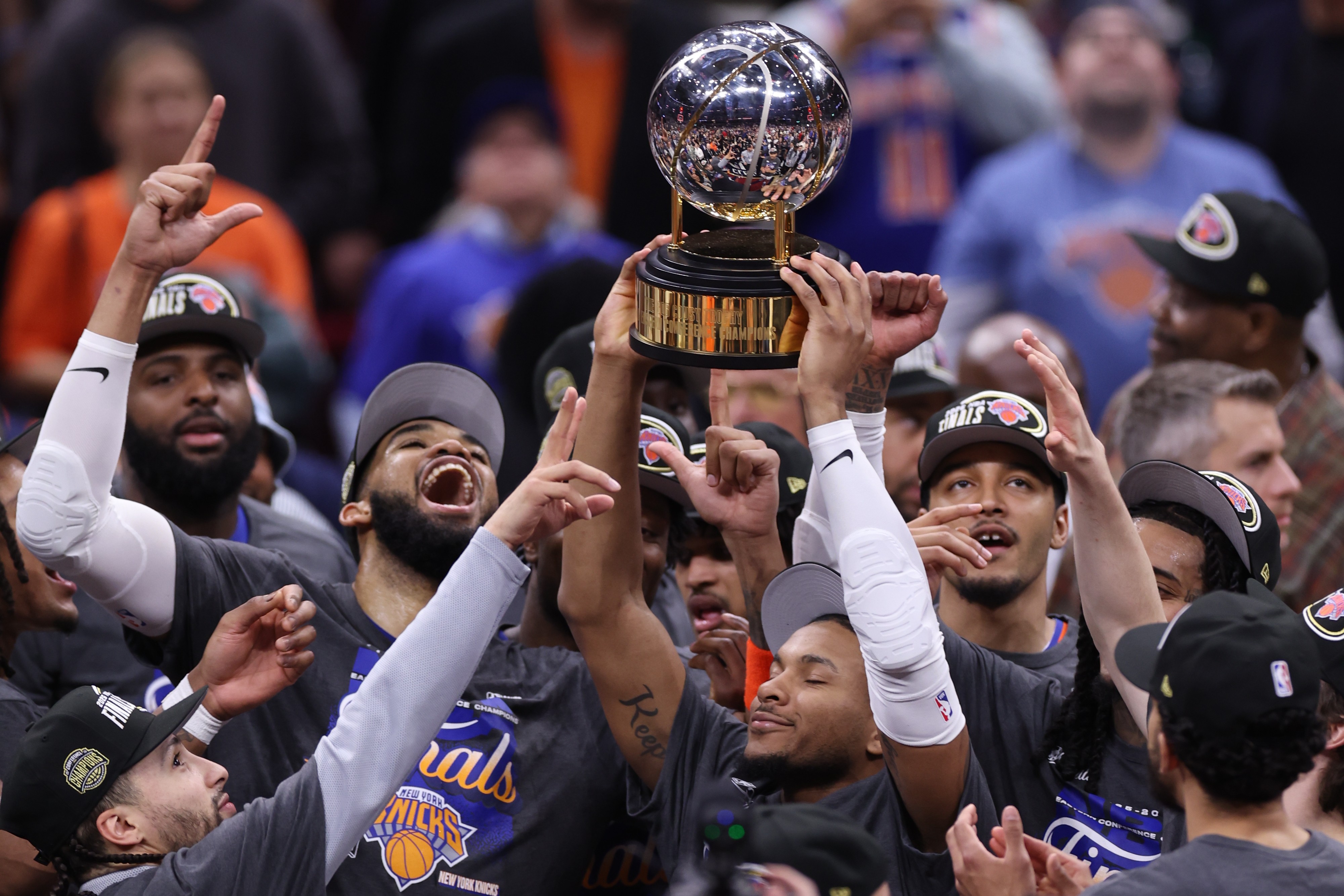 Members of the New York Knicks hold up the Eastern Conference Championship trophy, celebrating after a game.