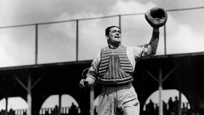 A black-and-white photograph of Moe Berg, catcher, in action