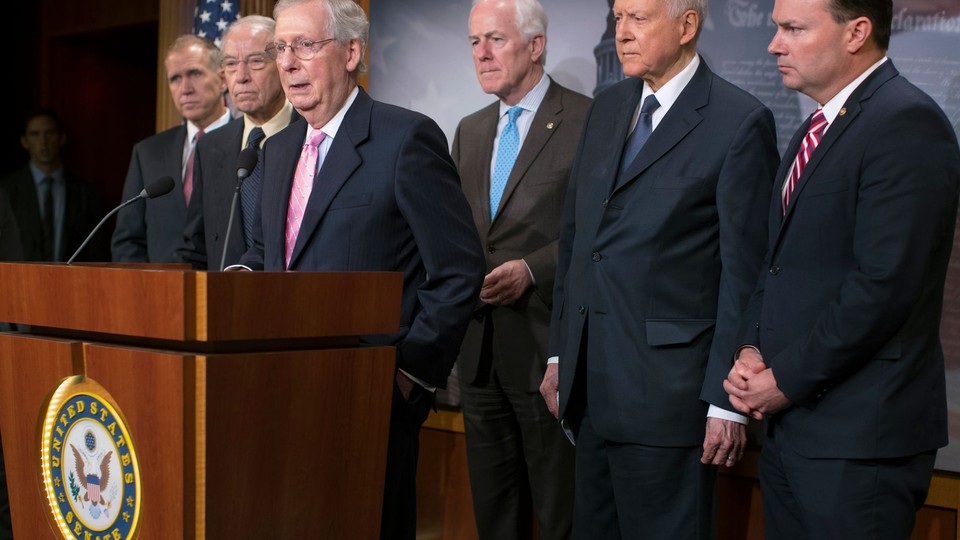 Mitch McConnell at a podium, surrounded by men in suits