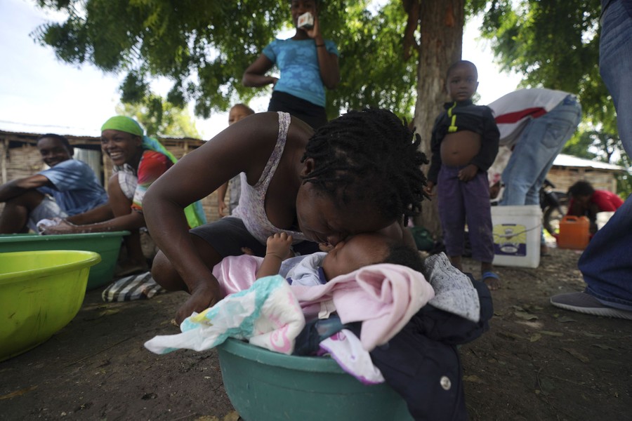 Una donna si strofina il naso con il nipotino neonato, tra gli altri, rifugiandosi nel cortile di una scuola.