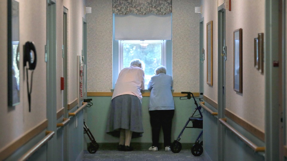 Two nursing-home residents look out a window.