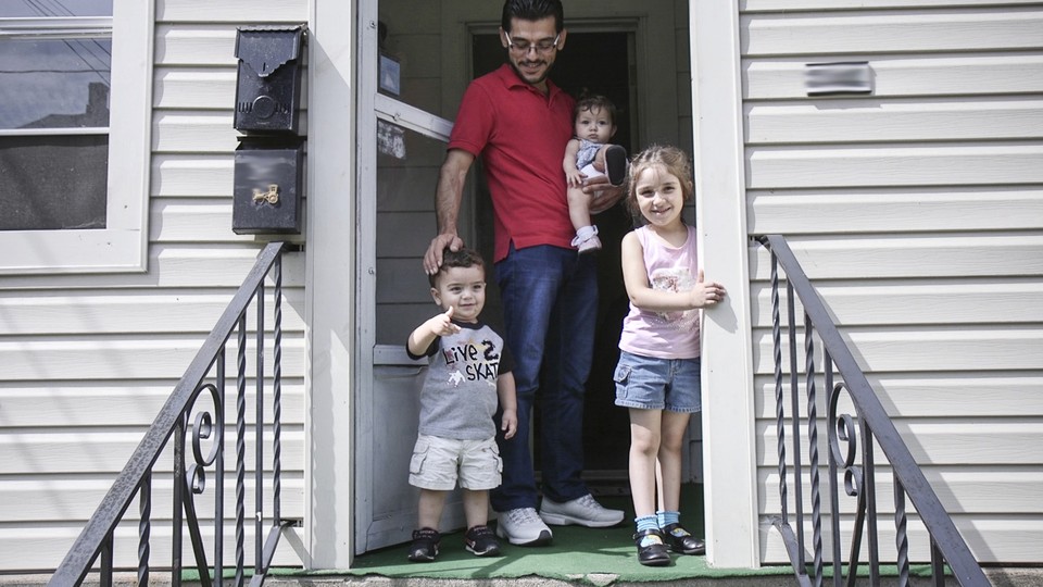 Mohammad Zkrit and three of his four children stand on the porch of their newly-rented home in Erie, Pennsylvania. The family fled the ongoing civil war in Syria and have been resettled in the United States.