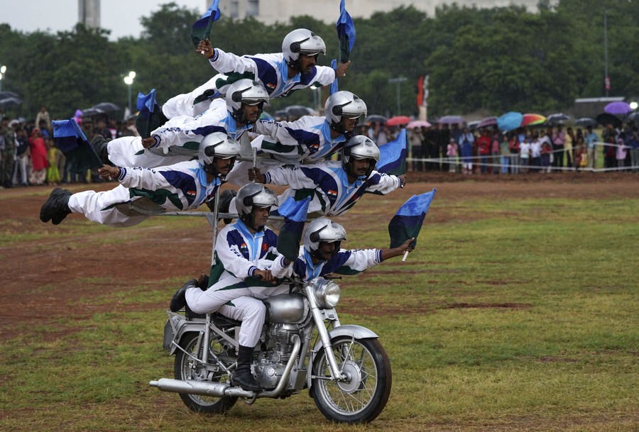 Seven soldiers form a pyramid on a specially rigged motorcycle, with the top five lying flat.