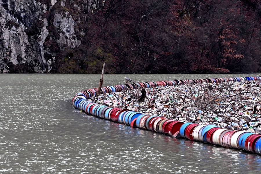 A floating boom holds back debris and garbage on a river.