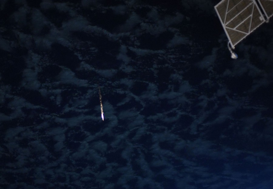 A fireball can be seen far away, moving past distant clouds.