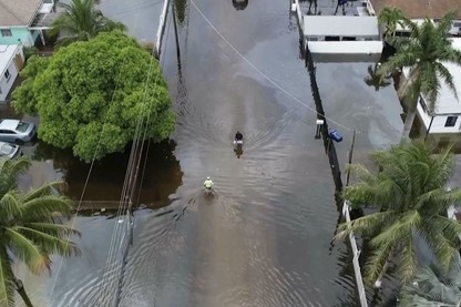 Two people make their way down a street in Miami so flooded that it's essentially a lake.