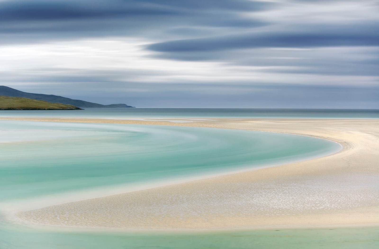 A sandy shoreline on a cloudy day. All of the edges and borders are soft and curved.