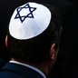 A man wearing a white yarmulke with a blue Star of David