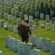 An Old Guard places American flags by headstones in Arlington National Cemetery.