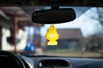 Two yellow air fresheners hang from a car mirror