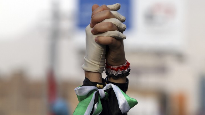 Women clasp hands during a pro-democracy march to demand Yemen's former President Ali Abdullah Saleh stand trial for the killings of protesters who demanded the end of his 33-year rule, in Sanaa on April 8, 2013.