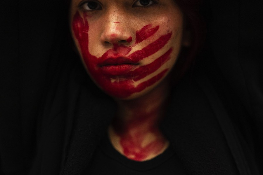 A woman with red hand-shaped face paint attends a protest.