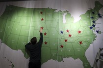 A man reaches up to touch a map of the United States decorated with red and blue stars.