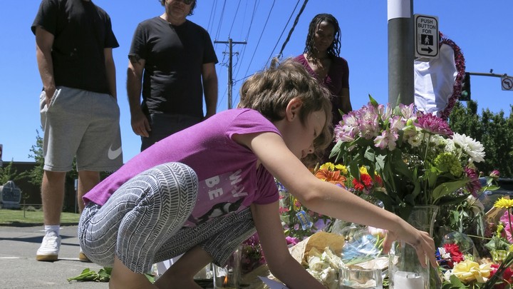 Angel Sauls, left, helps her stepdaughter, Coco Douglas arrange a sign and some painted rocks she made for a memorial in Portland, Oregon.