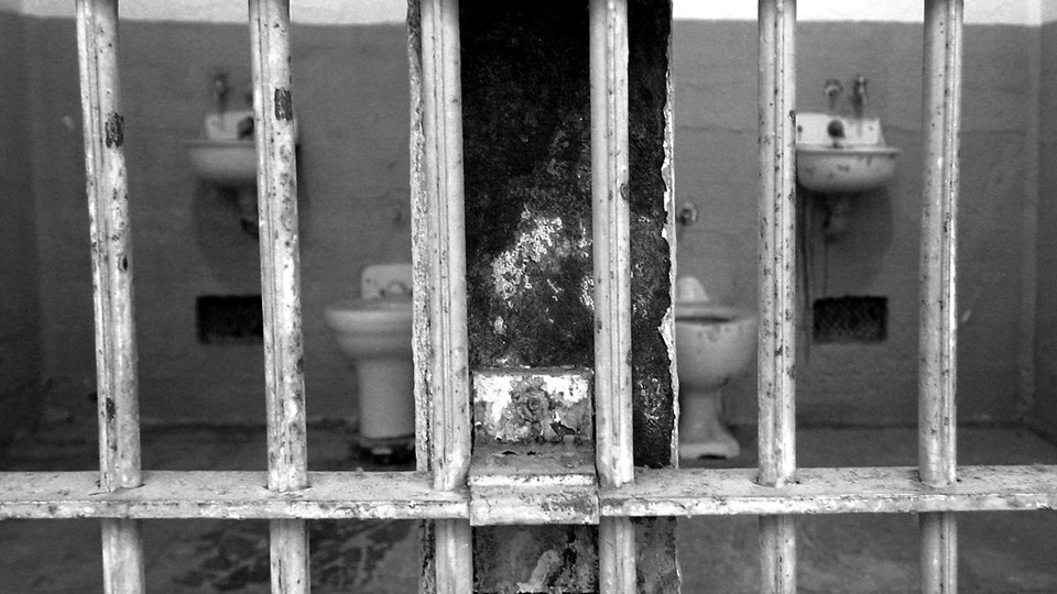 A black-and-white photo of prison cells behind bars