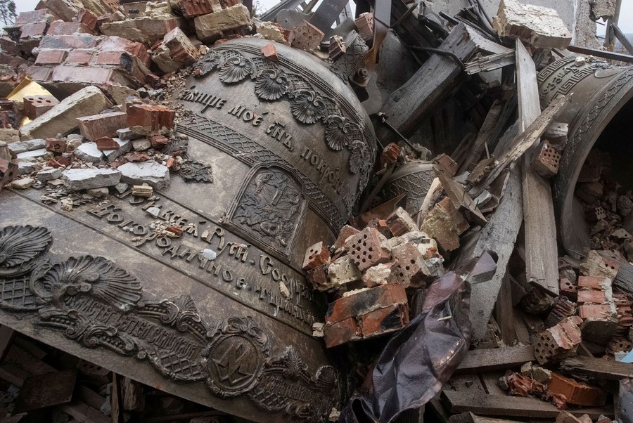 Large church bells sit in a pile of rubble.