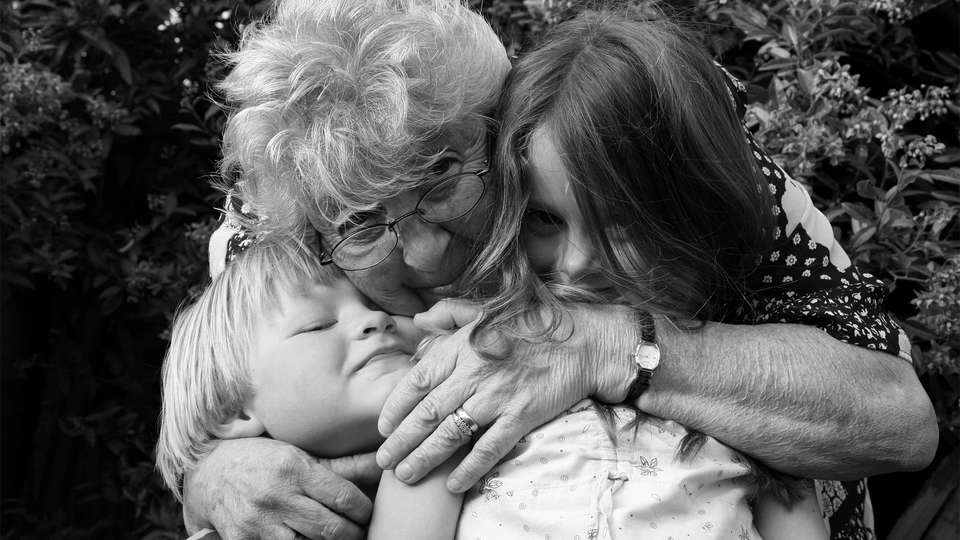 Black-and-white photo of a grandmother hugging two young children