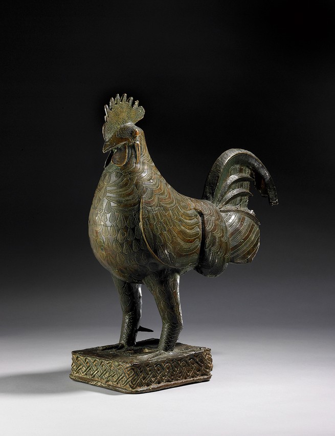 photo of a sculpture of a rooster with detailed plumage on a rectangular base