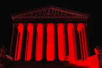 Image of the Supreme Court facade with a black background and red glow from the inside