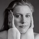 Black-and-white portrait of Greta Gerwig, with her hands cupping her face