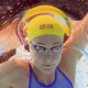 A close view of a swimmer's face, seen from below, underwater, as they swim in a race