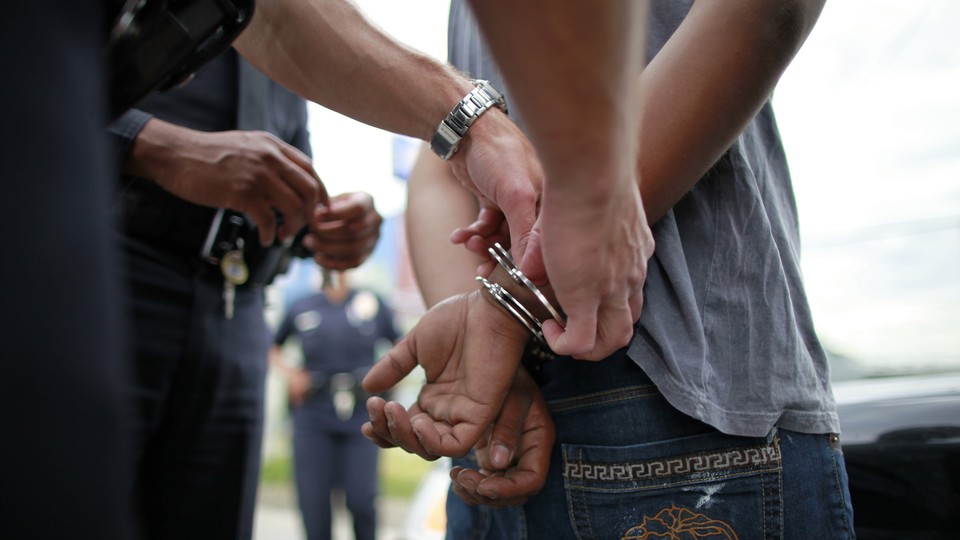 A police officer handcuffs a young man.