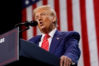 Photo of Donald Trump giving a speech at a podium with an American flag hanging behind him