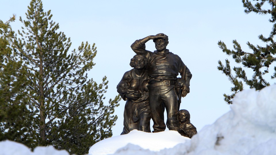A bronze statue of travelers surrounded by snow